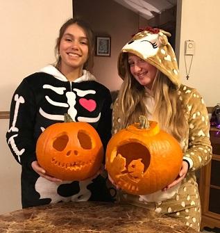 girls in costume holding pumpkins